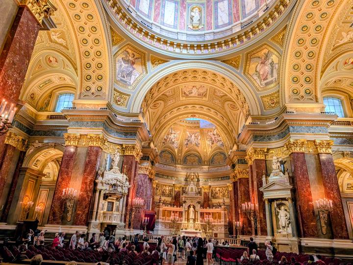 Opulent basilica interior with gilded columns, domed ceiling and chandeliers