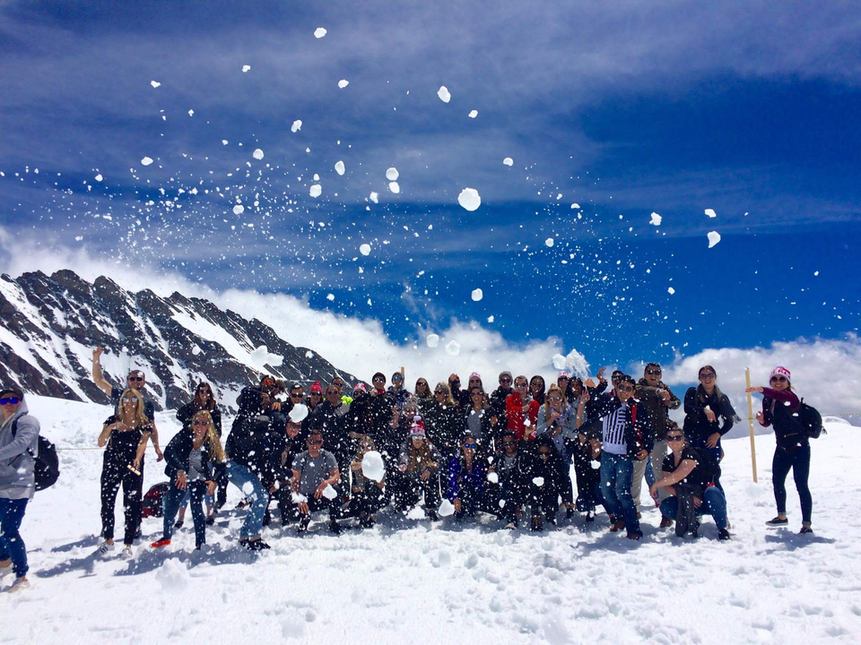 Groupe de personnes jouant dans la neige sous un ciel bleu.