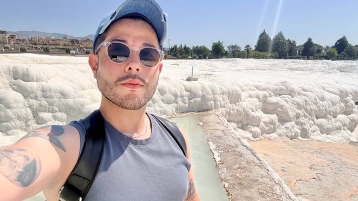 Self-portrait of a traveler standing beside the creamy white calcium pools of Pamukkale on a bright day.