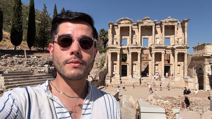 Traveler takes a selfie in front of the grand facade of the Library of Celsus at Ephesus under a clear sky.