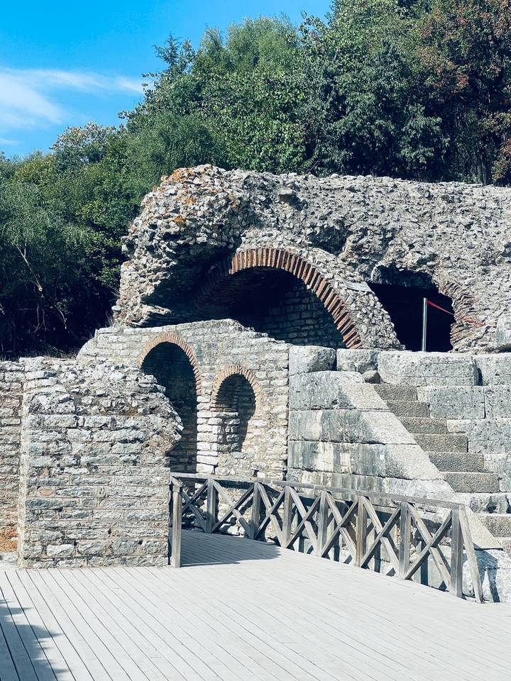 Weathered stone arches and brickwork of an ancient ruin bathed in sunlight.
