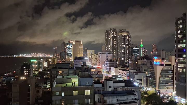 Nighttime cityscape of high-rise buildings and illuminated streets along the Colombo coastline.