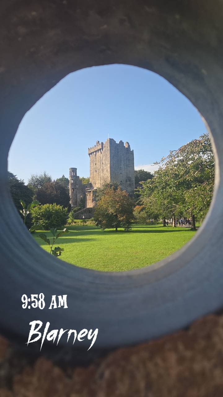 Stone Blarney Castle framed through a circular opening with lush green grounds