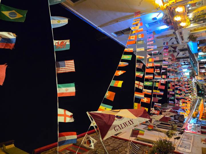 Nighttime street festooned with dozens of colorful international flags