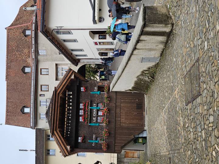 Charming cobbled street and chalet-style restaurant in Gruyères with visitors strolling uphill