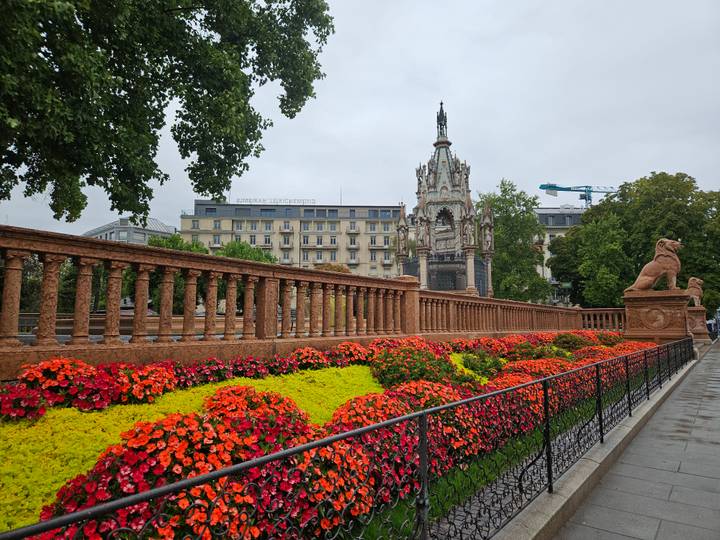 Vibrant flowerbeds line an ornate stone balustrade near the neo-Gothic Brunswick Monument in Geneva