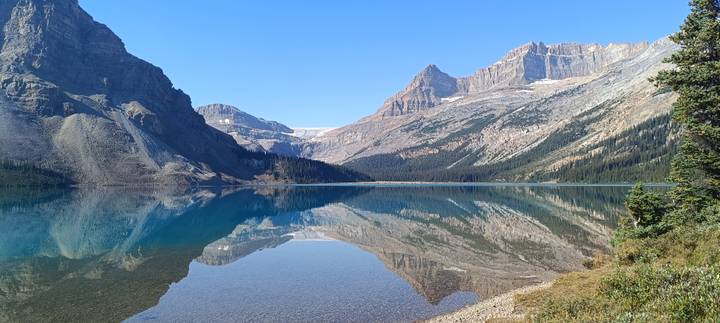 Pristine alpine lake with glassy reflection of surrounding peaks and forests