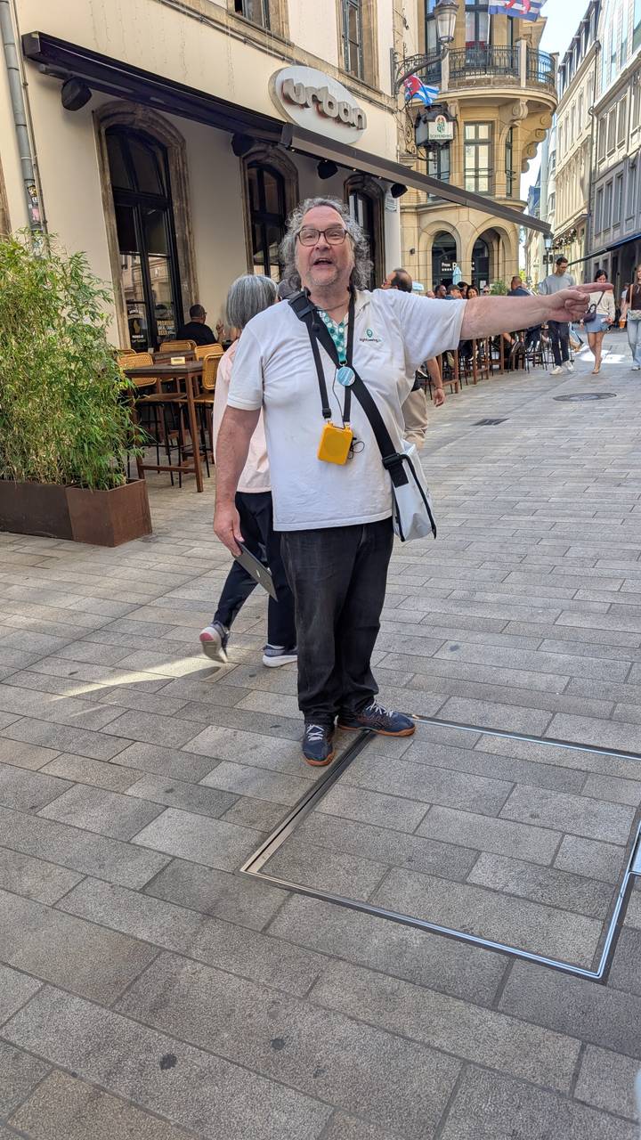 Man with camera bag stands on pedestrian street of modern city center