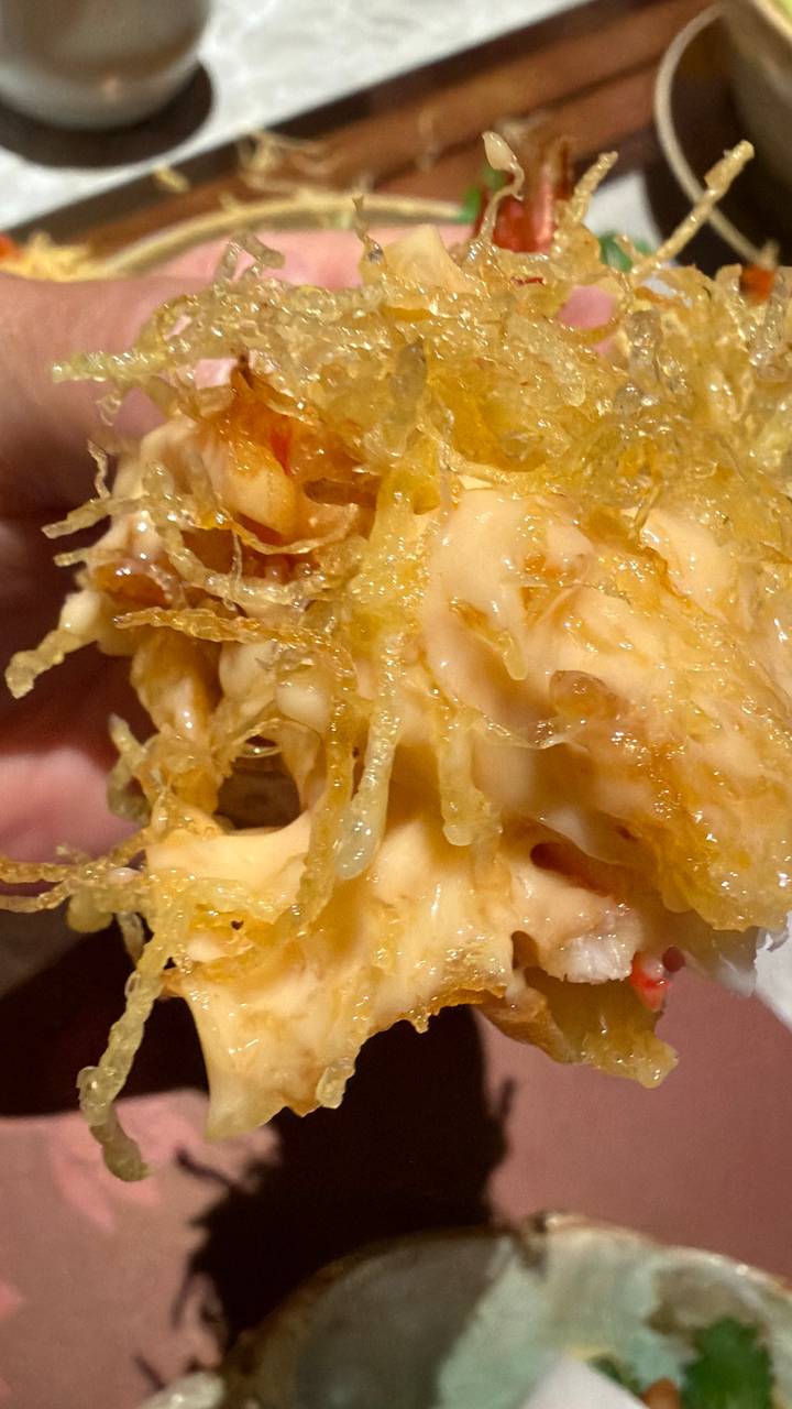 Macro close-up of crispy fried prawns coated in creamy sauce and shredded batter.