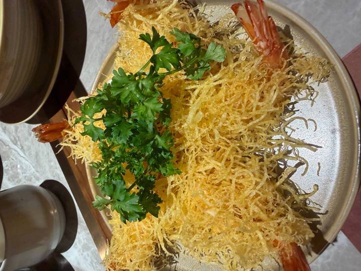Plate of deep-fried prawns topped with fine shredded batter and garnished with fresh parsley.