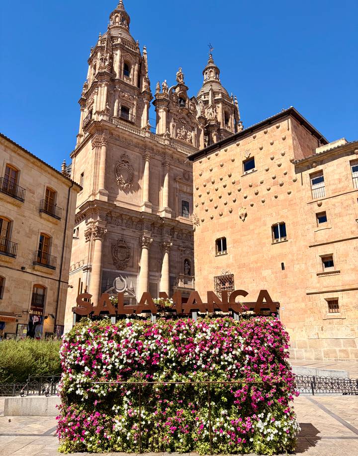Large SALAMANCA letter sculpture with grand sandstone cathedral backdrop under clear sky.
