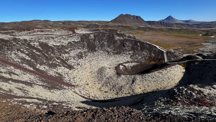 Large volcanic crater of Grábrók with lava fields and sharp peaks in clear morning light.