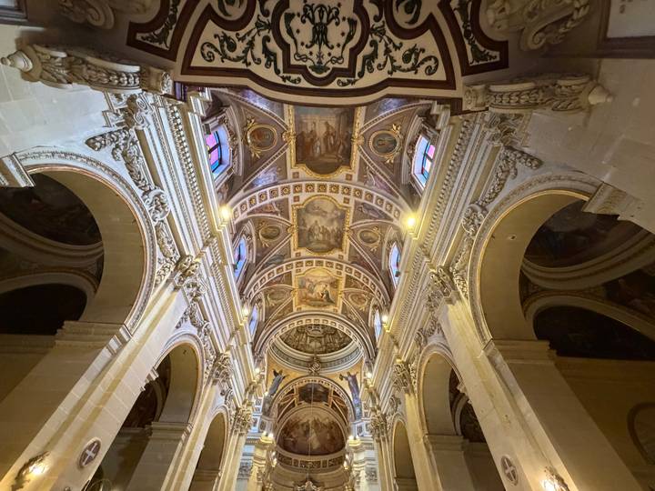 Ornate vaulted ceiling of a Maltese cathedral richly decorated with paintings and arches