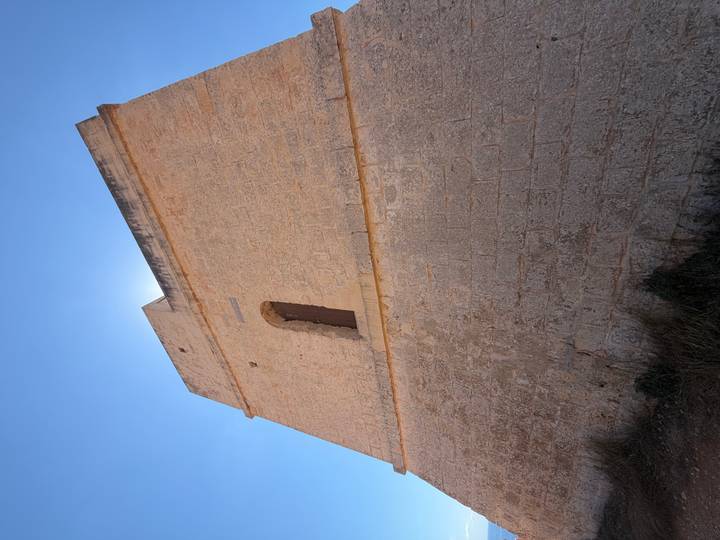 Tall stone watchtower viewed from base looking upward into bright sky