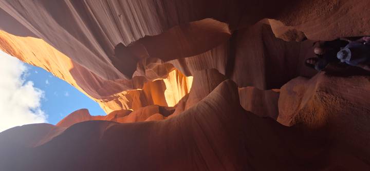 Narrow orange sandstone walls of Antelope Canyon with sunlight filtering through high above.