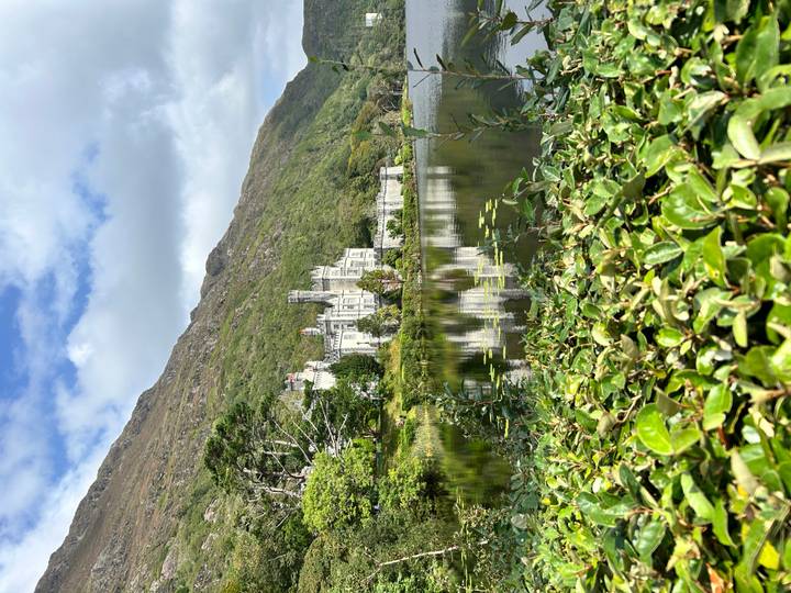 Elegant lakeside castle reflected in still water with lush greenery and a mountain backdrop