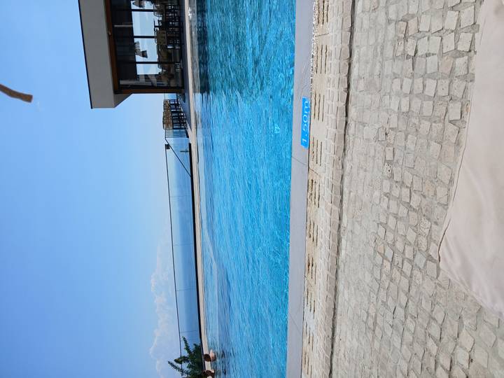 Infinity pool overlooking the open sea with clear skies and modern deck area.