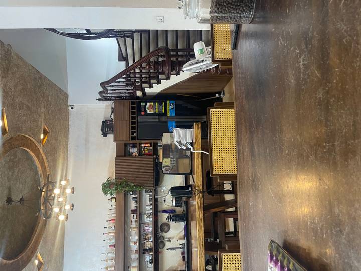 Interior of a cosy café with wooden furniture, staircase and shelves of coffee equipment.