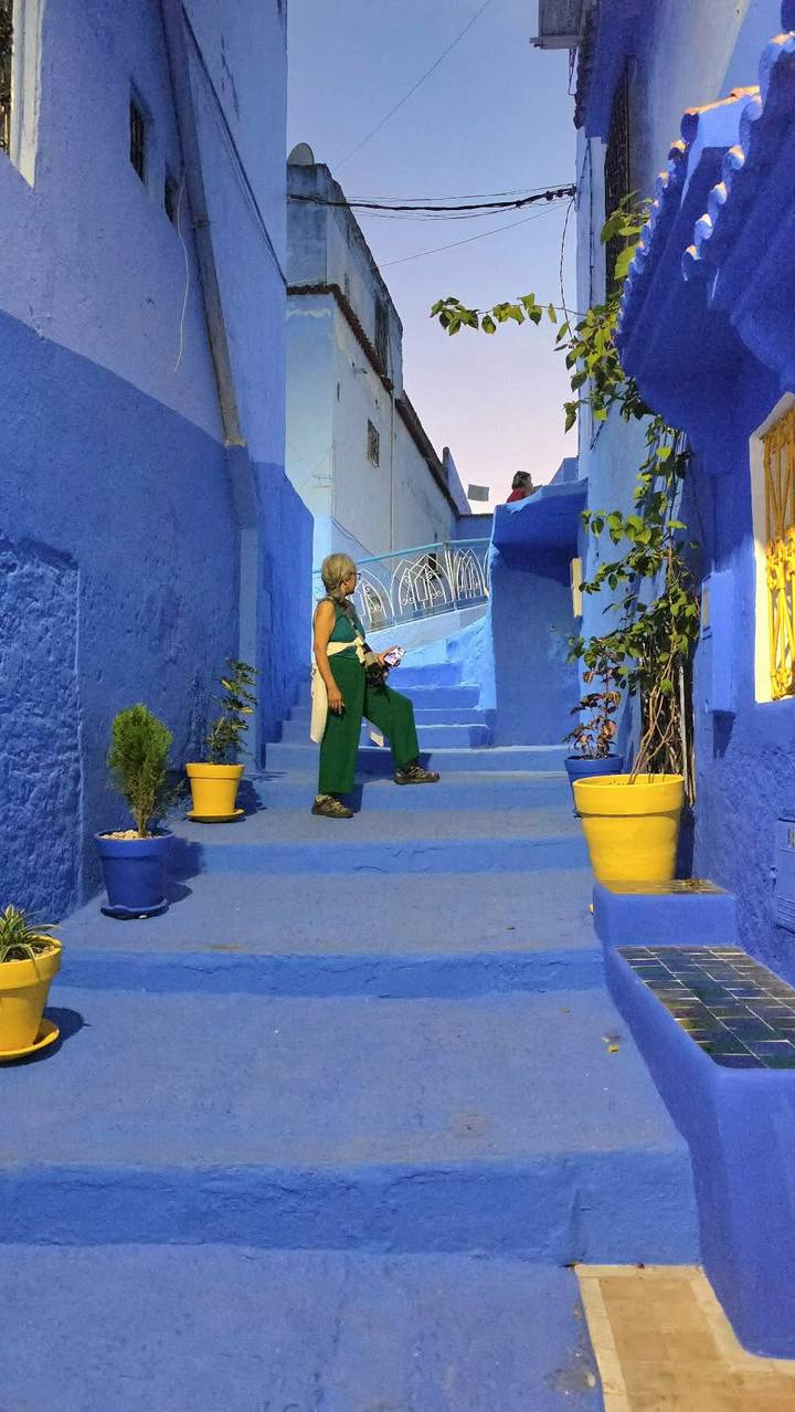 Traveler exploring the vivid blue alleyways of Chefchaouen with colorful pots and plants.