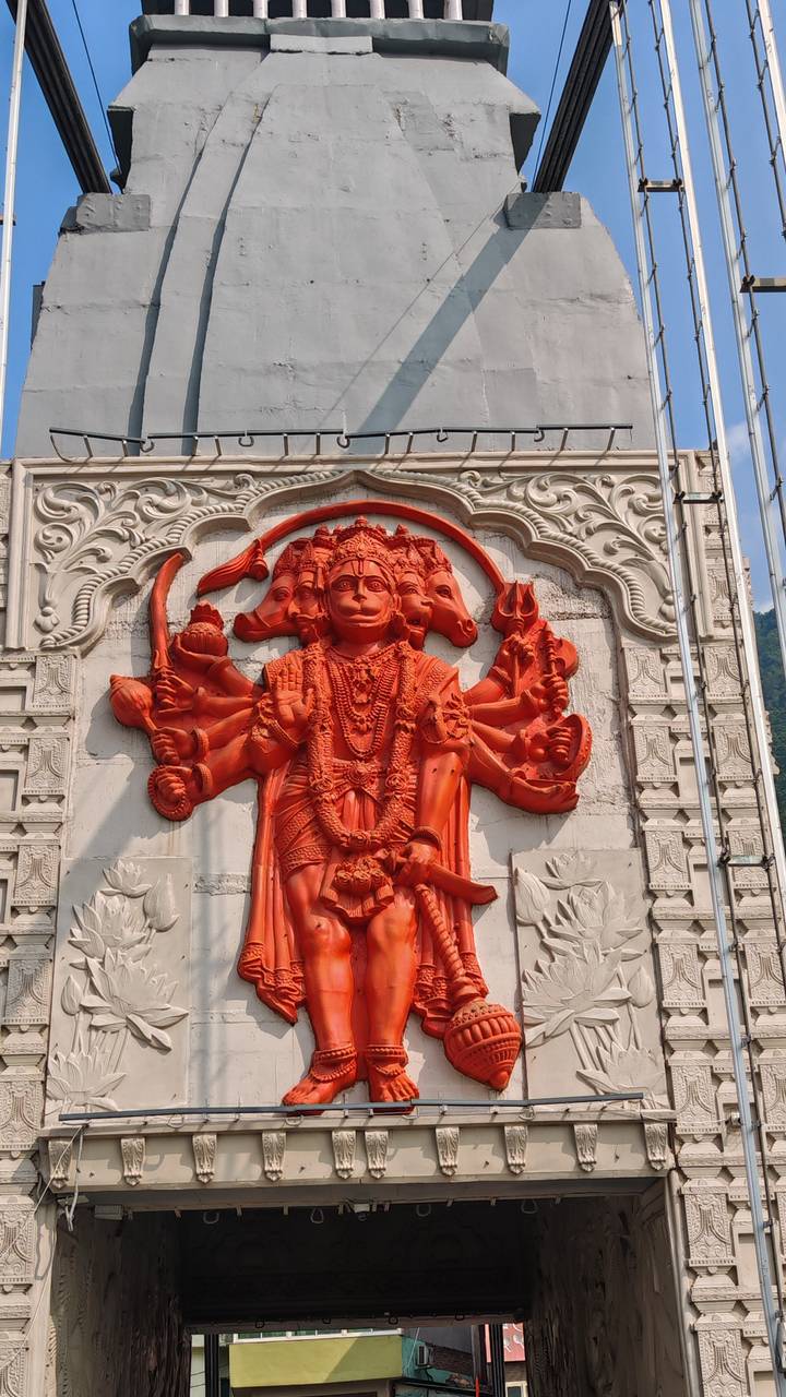 Vivid orange multi-headed Hindu deity relief sculpture on a grey temple wall