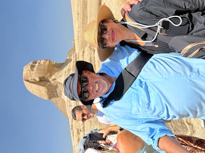 Travellers posing happily in front of the Sphinx under a bright blue Egyptian sky