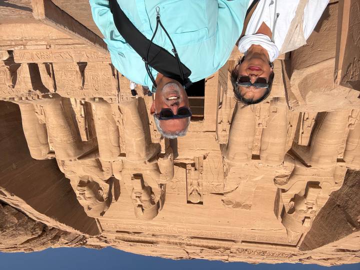 Couple standing before the colossal seated statues of Abu Simbel temple carved into sandstone