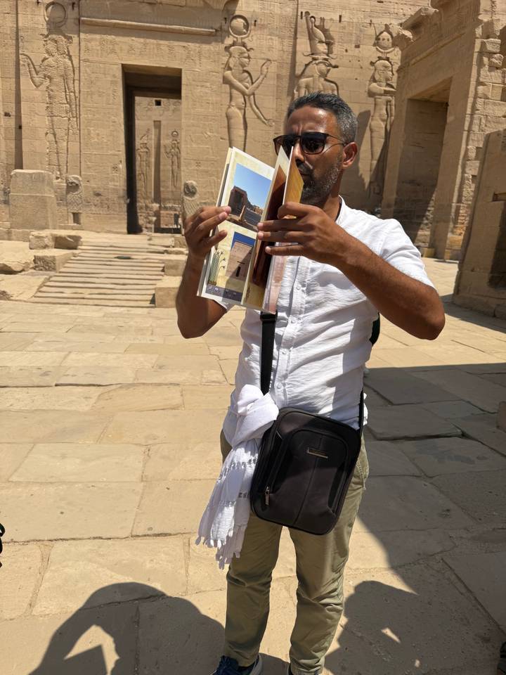 Guide holding up illustrative photos while explaining details inside an ancient stone temple