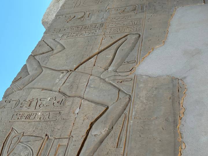 Close-up of ancient Egyptian relief carving showing a kneeling figure with hieroglyphs.