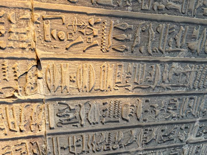 Detail of weathered hieroglyphic columns bathed in warm evening light.