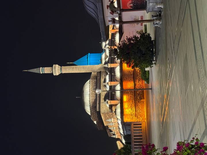 Night view of illuminated Mevlana Museum with turquoise dome and minaret