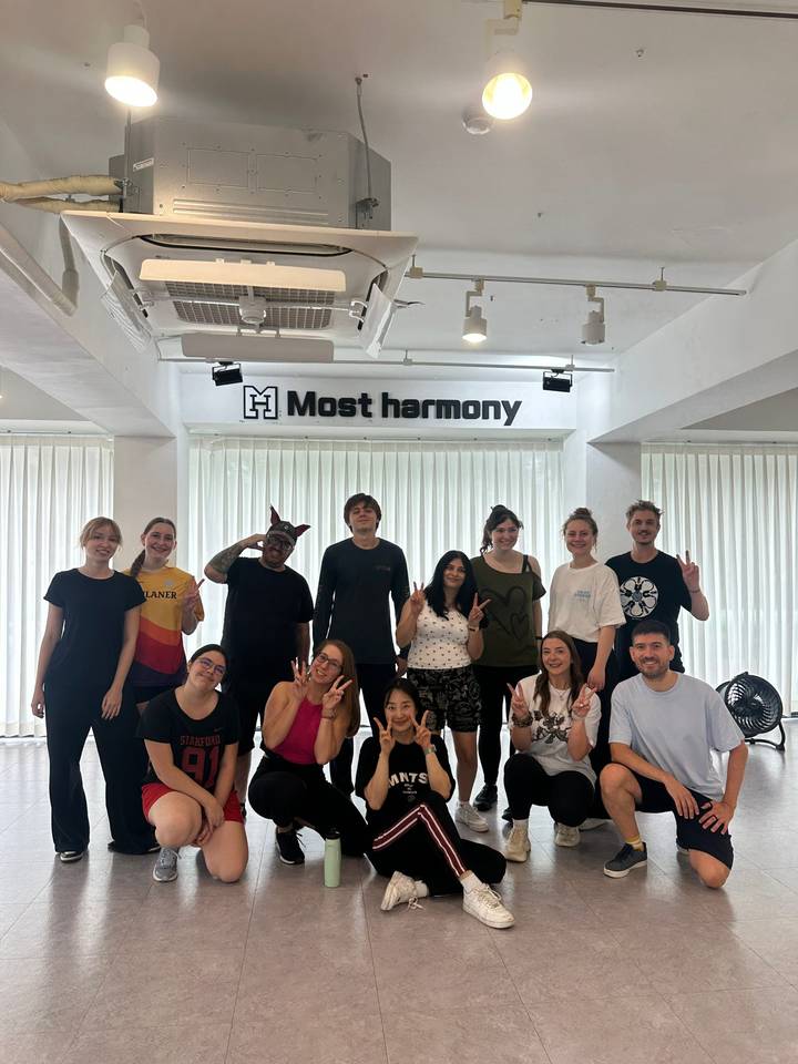 Large group posing together in a bright studio beneath a 'Most harmony' sign