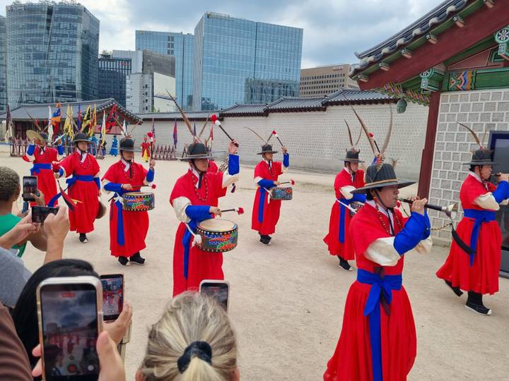 Traditional guard changing ceremony with performers in red robes at a Korean palace courtyard