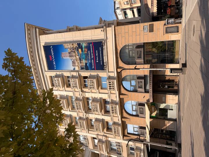 Tall apartment building with a large banner advertising Vlora Marina on a sunny city street