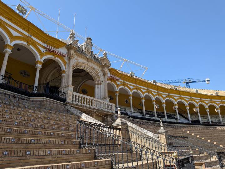 The curved rows of arches inside Seville’s historic bullring under a clear blue sky.