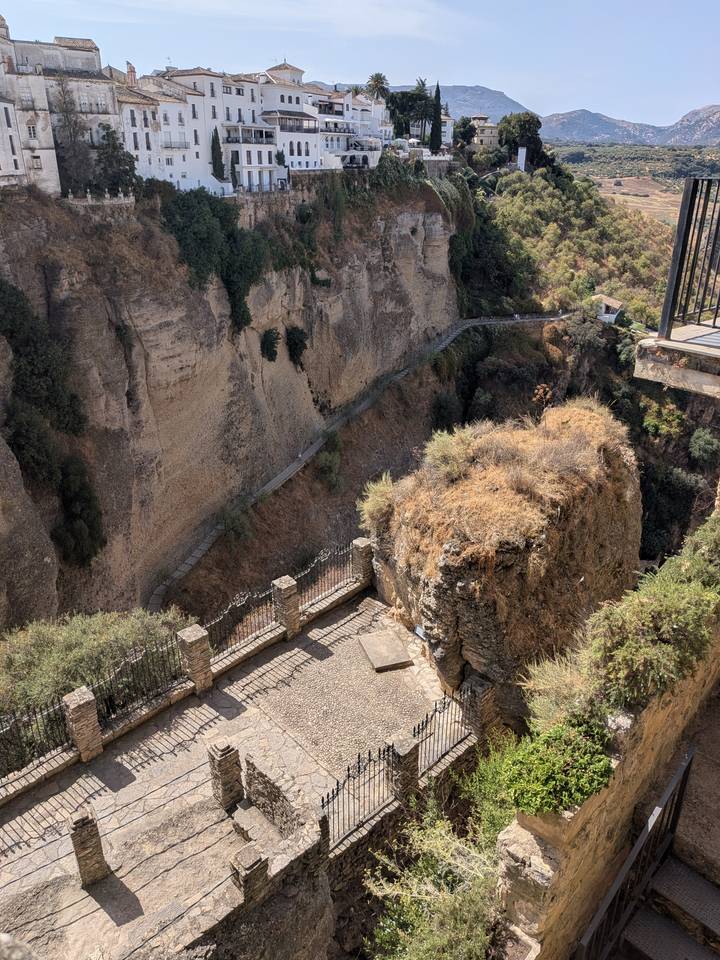 Rocky gorge in Ronda with steep cliffs, pathways and sun-baked vegetation.