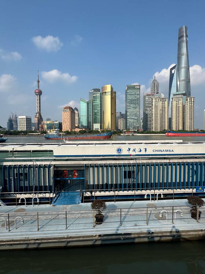 Riverfront view of Shanghai’s skyline with a cargo vessel and a floating dock marked CHINAMSA in the foreground.