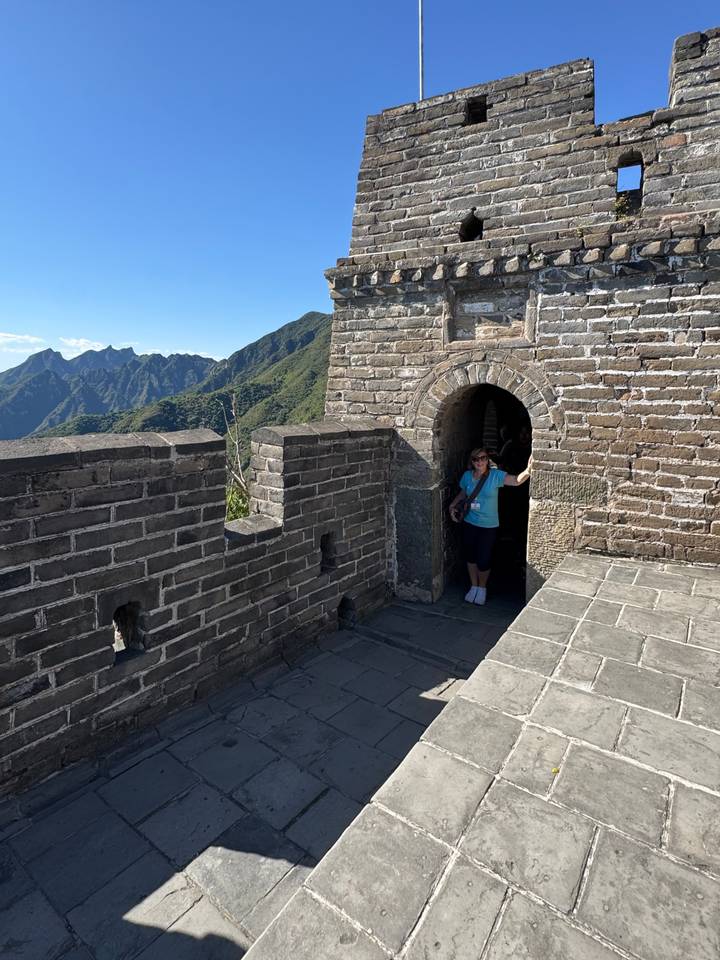 Visitor emerges from an arched doorway on the Great Wall with rugged mountain scenery behind.