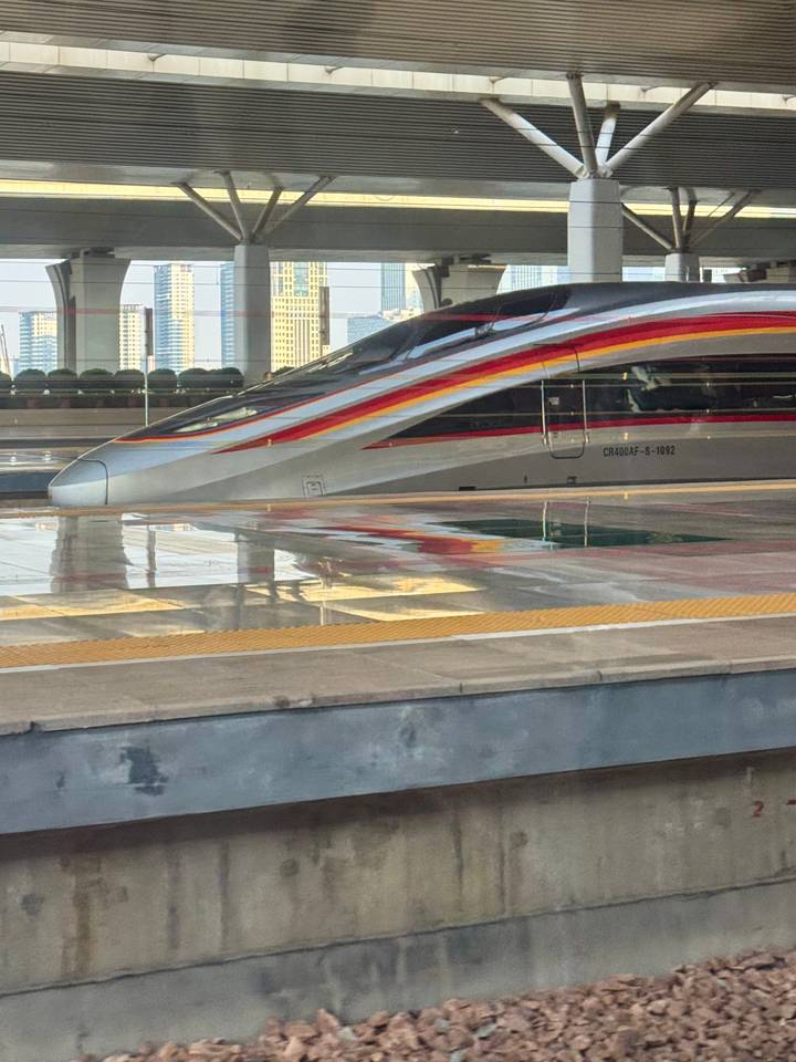 Sleek high-speed bullet train with red and yellow stripes waiting at a modern station platform.