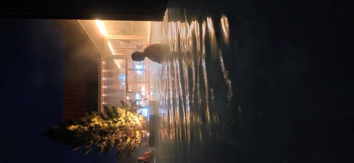 People relaxing in a steamy geothermal outdoor pool at night with soft lighting