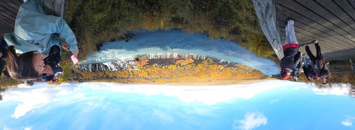 Panoramic view of a blue river and waterfall winding through colorful autumn forest