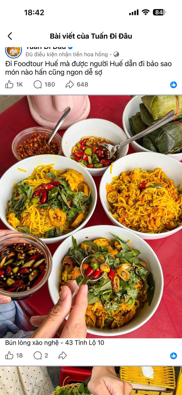 Bowls of vibrant yellow noodle salad garnished with basil, chilli and shrimp on a red table.