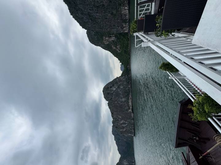 Overcast seascape of towering limestone island viewed from a cruise deck railing
