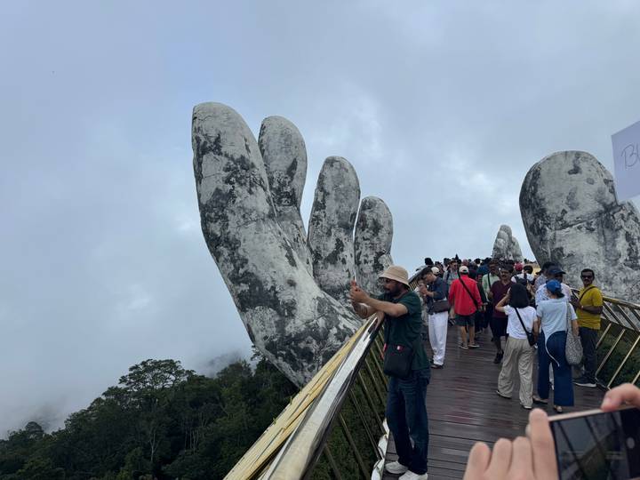 Crowds take selfies on mist-shrouded Golden Bridge held by giant stone hands