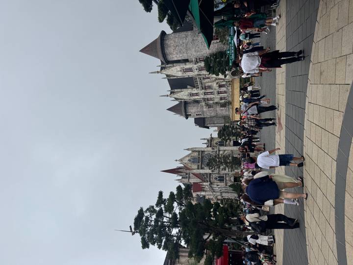 Theme-park style European castle buildings bustling with visitors under grey sky