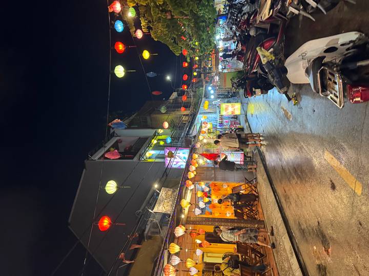 Rain-slicked street lined with colorful lanterns and shops in historic old town at night