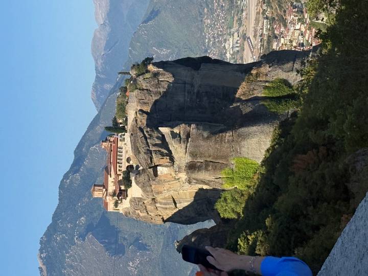 Iconic monastery perched on a towering Meteora cliff against a clear blue sky.