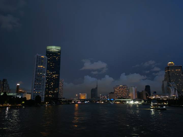 Nighttime Bangkok skyline with illuminated high-rise buildings reflecting on the Chao Phraya River