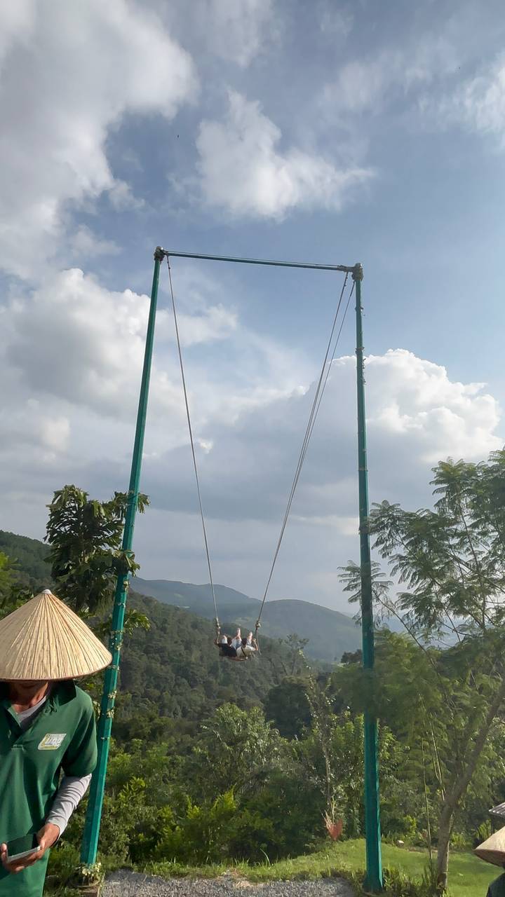 Vertical shot of green suspension bridge towers reaching to sky with clouds, partial composition
