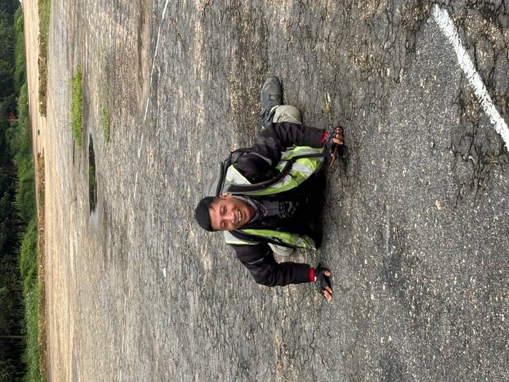 Smiling motorbiker lying playfully on a cracked asphalt surface wearing safety gear