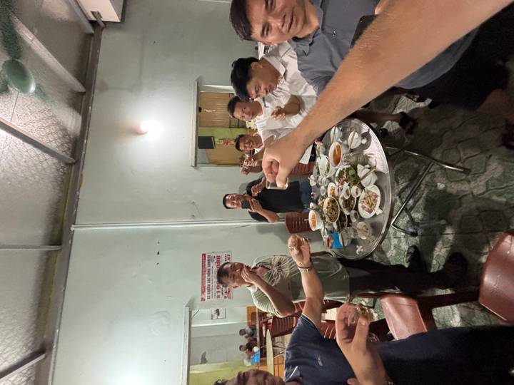 Group of men standing around a dinner table toasting with small glasses in a local restaurant